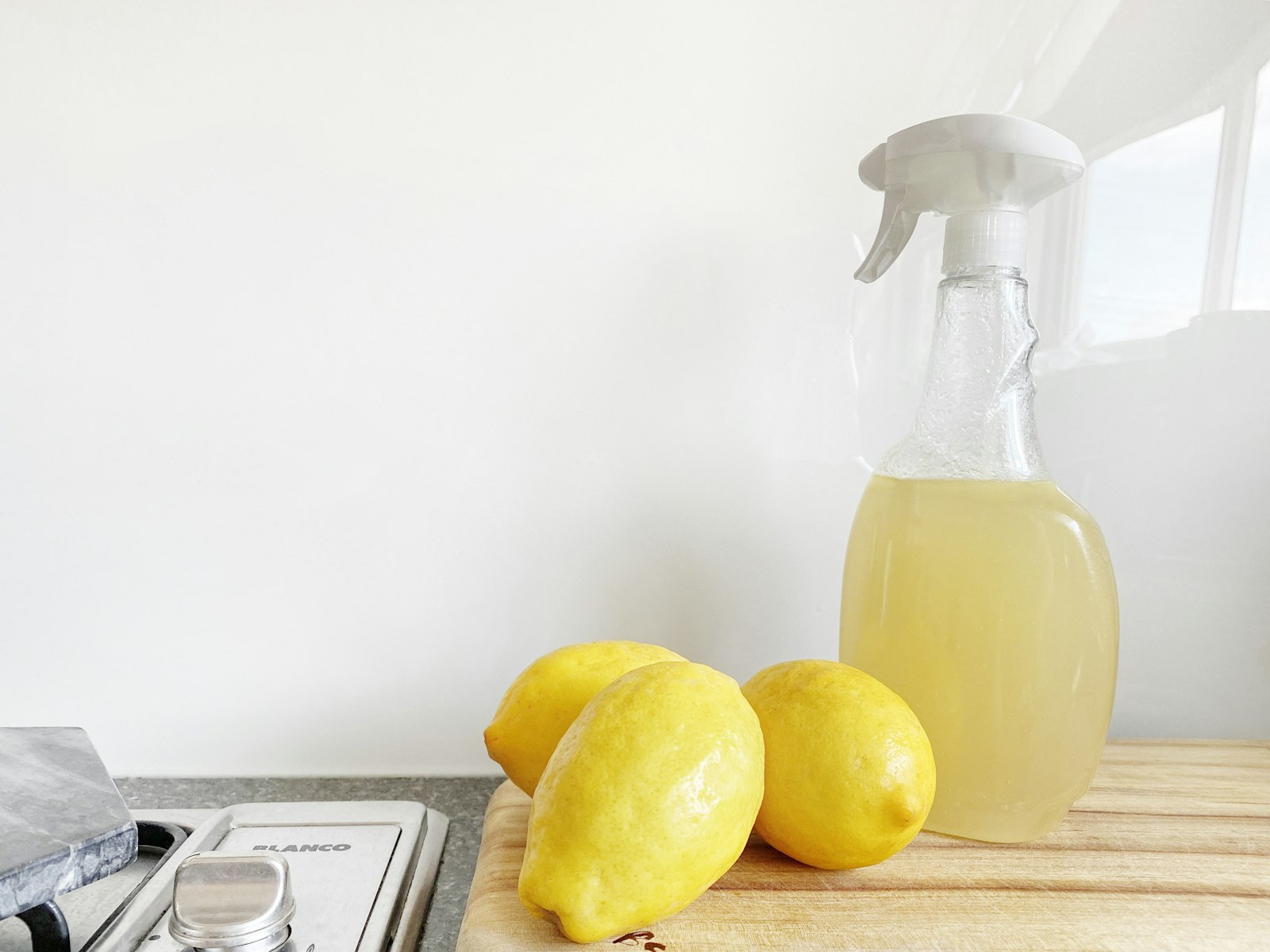 Fresh lemons beside a homemade cleaning spray bottle